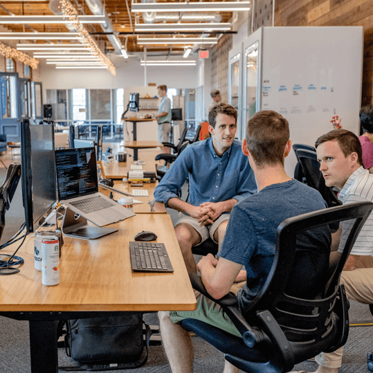 Three business professionals discussing recruiting strategies, focused on helping candidates connect with available positions through personalized support as part of Tailored Technology Staffing Solutions.